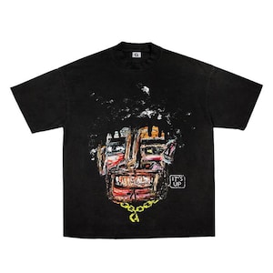 Könnte beinhalten: Schwarzes T-Shirt mit einem farbenfrohen, abstrakten Gesichtsdesign mit einer goldenen Kette. Das Kunstwerk enthält Rot-, Orange- und Brauntöne. Der Text "IT'S UP" befindet sich in einem kleinen weißen Feld unten rechts.