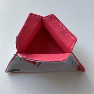 K&ouml;nnte beinhalten: Ein dreieckiger Stoffaufbewahrungskorb mit rosa Futter und einem Wassermelonenmuster auf der Au&szlig;enseite.