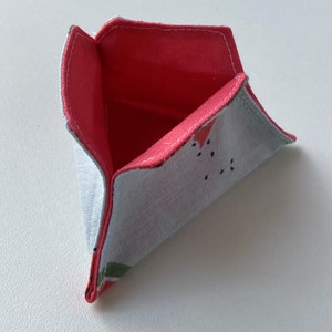 K&ouml;nnte beinhalten: Eine kleine dreieckige Stofftasche mit rotem Futter und einem Wassermelonenmuster auf der Au&szlig;enseite.