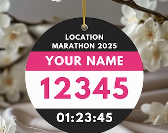 May include: A round, black and white marathon ornament with the text "LOCATION MARATHON 2025" and "YOUR NAME". The ornament has a pink stripe and the numbers "12345" in pink. The time "01:23:45" is displayed at the bottom.