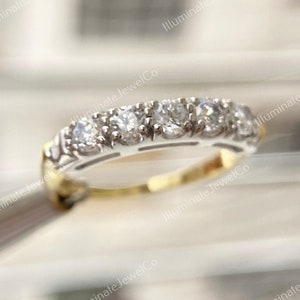 May include: A delicate gold band with a row of sparkling diamonds set in a white metal. The band is a classic and elegant design.