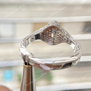 May include: A silver engagement ring with a large oval-shaped center stone and a detailed, intricate design. The ring is set on a white background.
