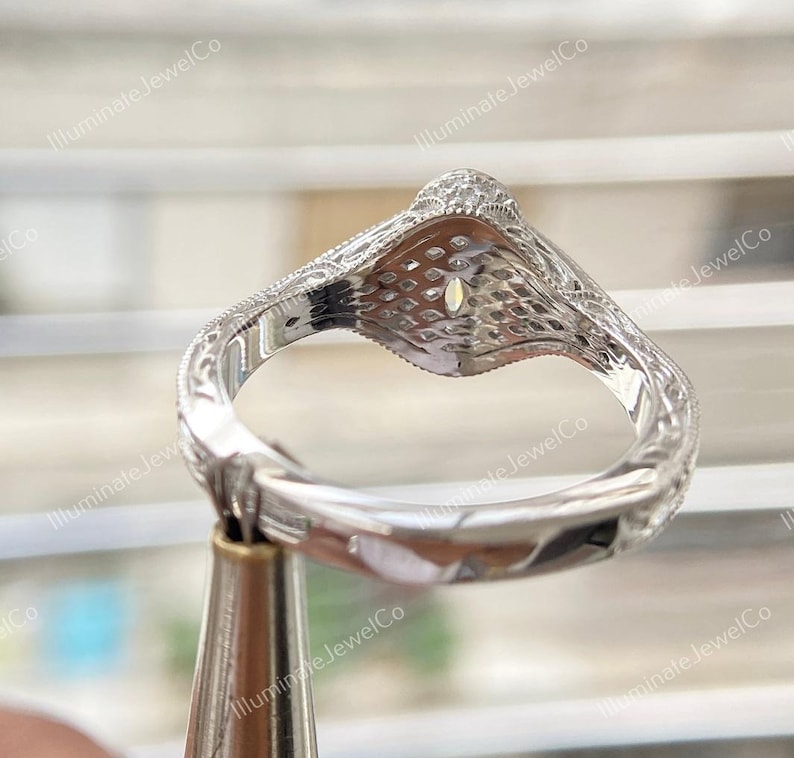 May include: A silver engagement ring with a large oval-shaped center stone and a detailed, intricate design. The ring is set on a white background.