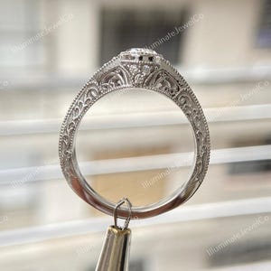 May include: A silver engagement ring with a round center stone and intricate filigree detailing on the band.