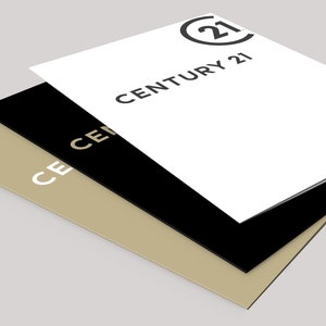 May include: Three layered business cards in white, black, and tan. The top card is white with the Century 21 logo and text in black. The black card is in the middle, and the tan card is on the bottom.
