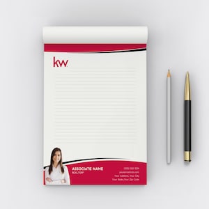 May include: A white notepad with a red and black accent design, the "kw" logo, and a photo of a woman. A pencil and a pen are next to the notepad. The notepad has lined paper.