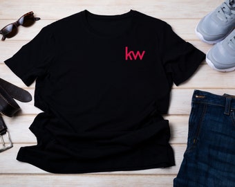 May include: Black t-shirt with a red "kw" logo on the front. The shirt is laid flat on a light wood surface.