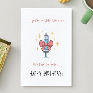 Könnte beinhalten: Weiße Geburtstagskarte mit einem Cartoon-Spritzen-Design, einer rosa Schleife und dem Text "If you're getting this card... it's time for Botox. HAPPY BIRTHDAY!" auf weißem Hintergrund.