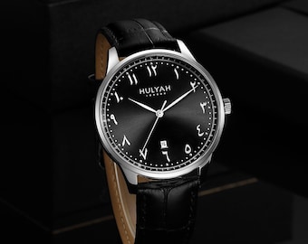 May include: A black wristwatch with a silver band and Arabic numerals on the face. The watch face says "HULYAH LONDON".