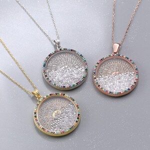 May include: Three necklaces with round pendants. The pendants are filled with small, clear stones and surrounded by a ring of colorful gems. The chains are gold, silver, and rose gold.