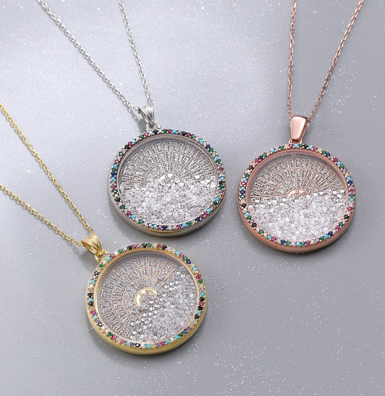 May include: Three necklaces with round pendants. The pendants are filled with small, clear stones and surrounded by a ring of colorful gems. The chains are gold, silver, and rose gold.