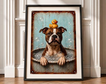 May include: Framed metal sign featuring a brown and white dog in a bathtub with bubbles, wearing a yellow rubber ducky on its head. The background is a light blue with bubbles, and the sign has a distressed, vintage look.