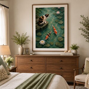 May include: A framed wall art print featuring a calico cat sitting on a stone ledge overlooking a pond with two orange and white koi fish, green lily pads, and white and pink water lilies floating on the dark green water surface.