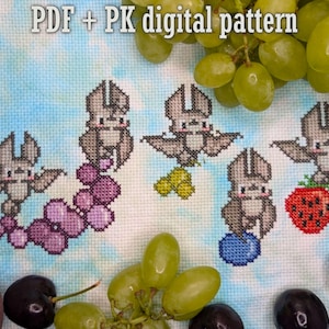 May include: Cross-stitch pattern featuring five gray bats with outstretched wings, each holding a different fruit: grapes, a yellow fruit, a blueberry, and a strawberry. The text "PDF + PK digital pattern" is at the top. The background is a light blue and white fabric.
