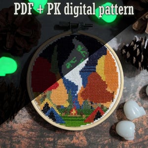 May include: A cross-stitch embroidery in a wooden hoop, featuring a colorful landscape design with a campfire and tents. The text "PDF + PK digital pattern" is at the top. The image is decorated with pinecones and glowing skull-shaped objects.