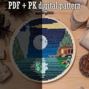 May include: A cross-stitch pattern of a night scene with a camper van, trees, a lake, and a full moon. The pattern is in a wooden embroidery hoop and is ready to be stitched.