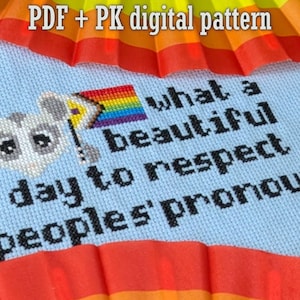 May include: A cross-stitch design on light blue fabric features a cartoon mouse holding a rainbow flag. The text reads "what a beautiful day to respect people's pronouns." A rainbow fan is at the top and bottom.