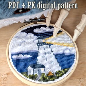 Może przedstawiać: Haft krzyżykowy w drewnianym tamborku przedstawia scenę latarni morskiej z niebieskim morzem, białymi chmurami i ciemnym niebem. Tekst "PDF + PK digital pattern" znajduje się na górze. Scena jest trzymana przez szkieletową dłoń.