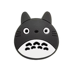 Pode incluir: Um rosto de personagem de desenho animado em preto e branco com olhos grandes e uma barriga branca. O personagem tem orelhas pontudas e um nariz pequeno. O design é um personagem de anime popular.