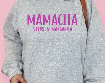 May include: Gray sweatshirt with the text "Mamacita Needs a Margarita" in pink lettering.