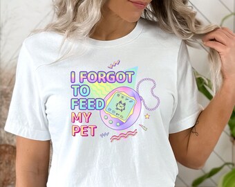 May include: White t-shirt with a graphic of a Tamagotchi and the text "I forgot to feed my pet".