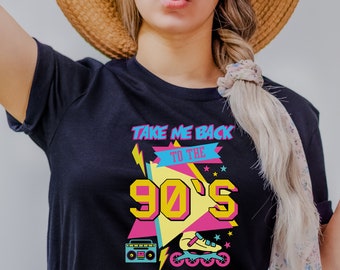 May include: Black t-shirt with a graphic design featuring a retro 90s theme. The design includes the text "Take Me Back To The 90's" in a colorful, geometric font. The graphic also includes a boombox, rollerblades, and stars.