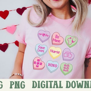 Puede incluir: Una camiseta rosa con un dise&ntilde;o de corazones de caramelo coloridos. Los corazones tienen diferentes lemas, incluyendo "Be Mine", "Save Lives", "Nurse", "XOXO", y "Shots Shots Shots".