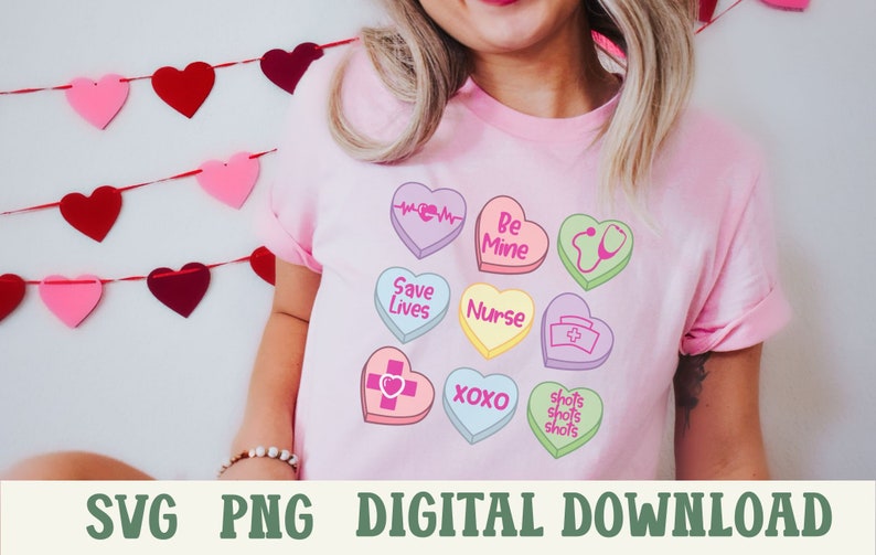 Puede incluir: Una camiseta rosa con un dise&ntilde;o de corazones de caramelo coloridos. Los corazones tienen diferentes lemas, incluyendo "Be Mine", "Save Lives", "Nurse", "XOXO", y "Shots Shots Shots".