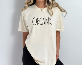 May include: A cream colored t-shirt with the word "ORGANIC" printed in black on the front.