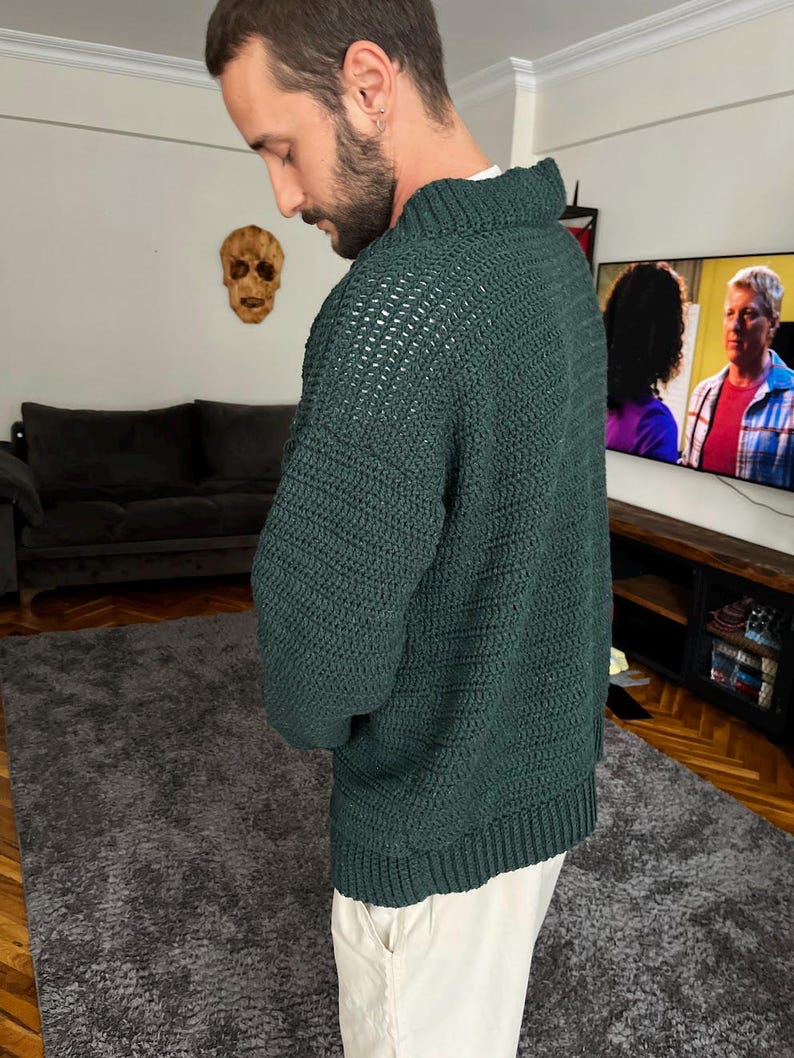 May include: A dark green knitted sweater with a textured pattern. The sweater has a high neckline and long sleeves.