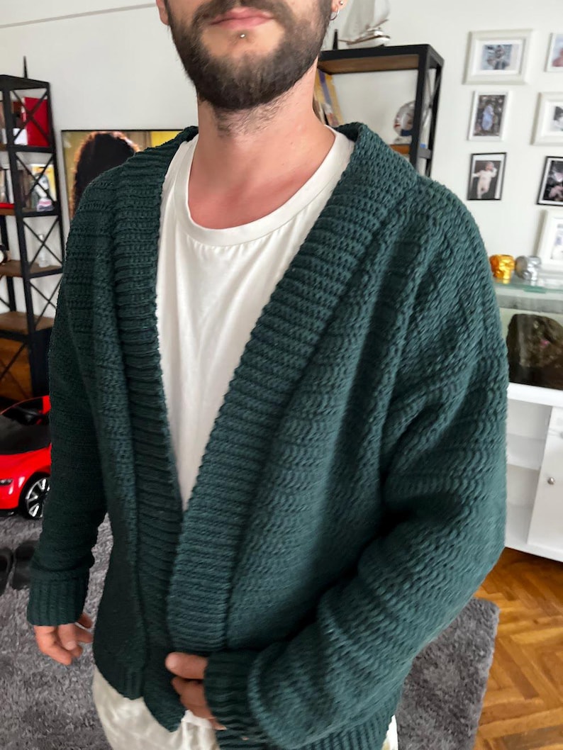 May include: A dark green knitted cardigan with a deep V-neck and long sleeves.