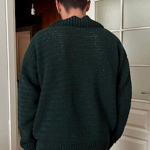 May include: A dark green knitted sweater with a high neck and long sleeves.