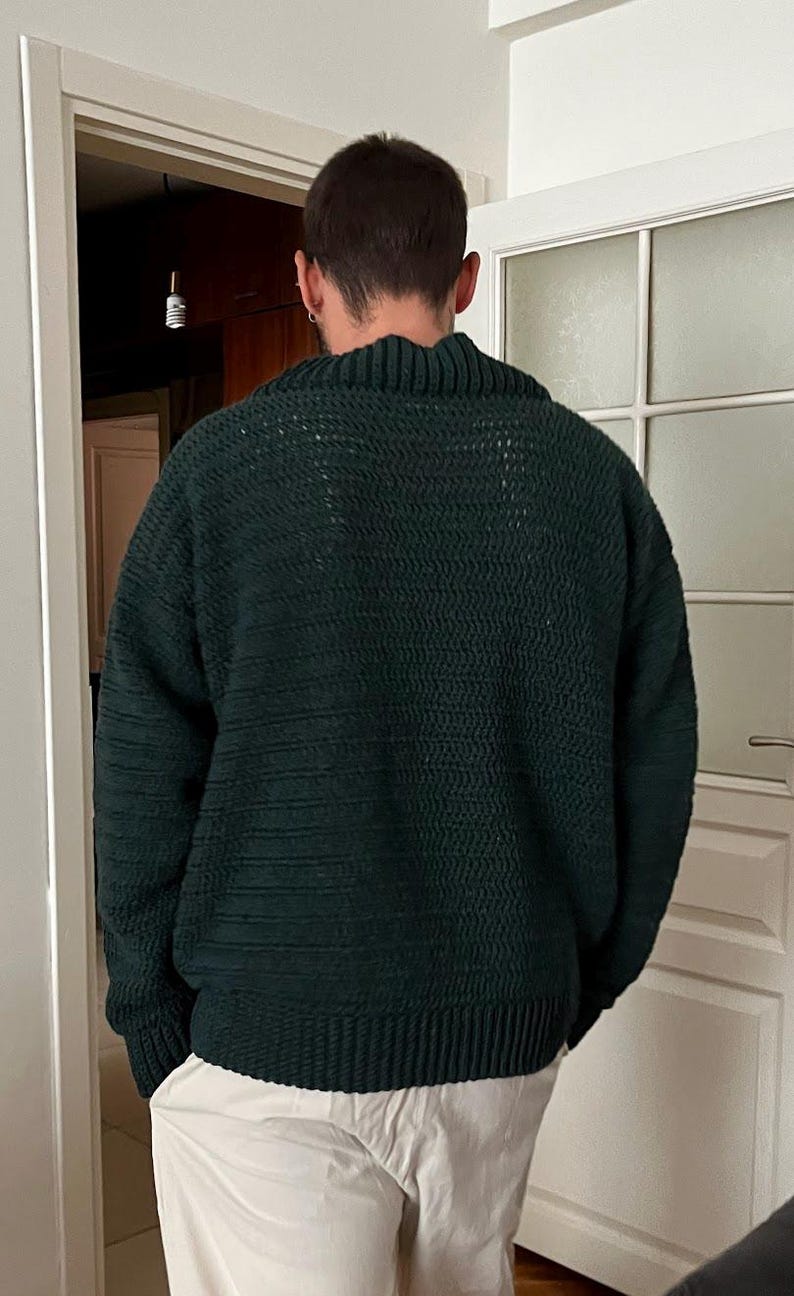 May include: A dark green knitted sweater with a high neck and long sleeves.