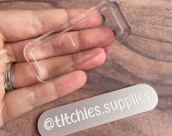 May include: A clear plastic rectangular box with rounded edges and a silver rectangle with the text "@titchies.supplies" on it.
