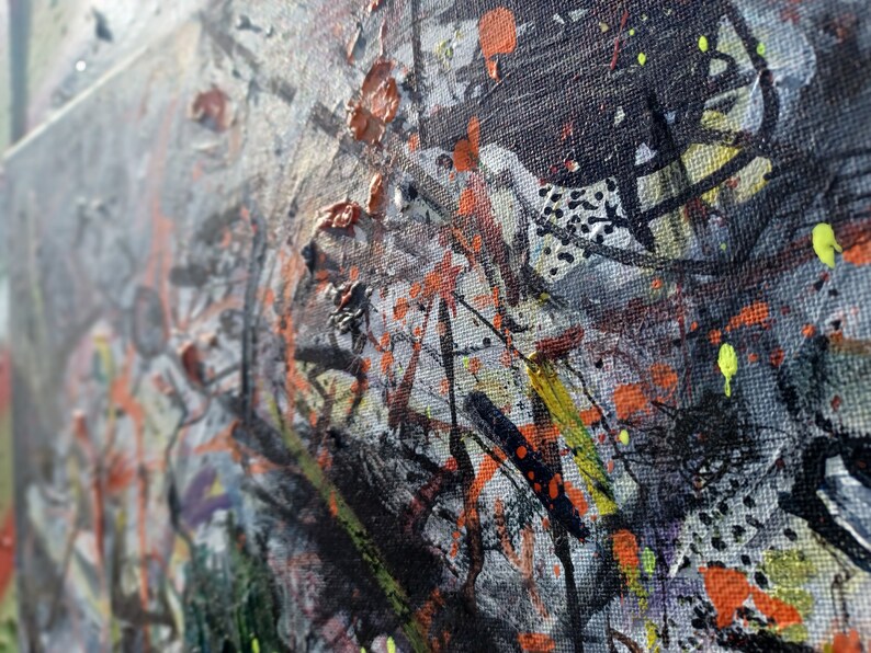 May include: Abstract painting on canvas with a textured surface. The painting features a variety of colors, including black, white, orange, yellow, and green. The paint is applied in a variety of ways, including splatters, drips, and brushstrokes.