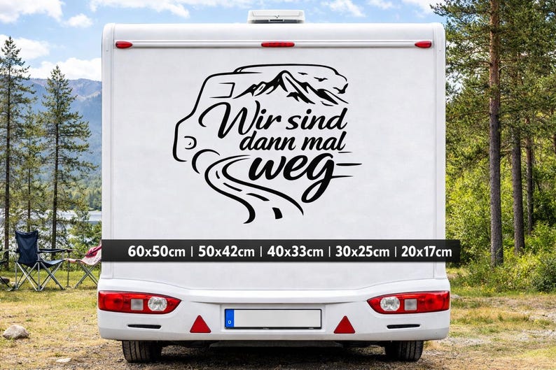May include: A black vinyl decal applied to the rear of a white camper van. The design features a stylized camper van outline, mountain peaks, and a winding road, accompanied by the German text "Wir sind dann mal weg" in a cursive script.