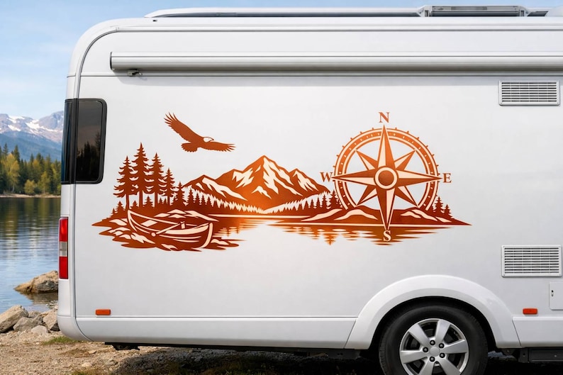 May include: A copper-colored vinyl decal applied to the side of a white camper van. The graphic features a mountain range, a forest of pine trees, a small boat on water, a flying eagle, and a large compass rose with the letters N, S, E, and W.