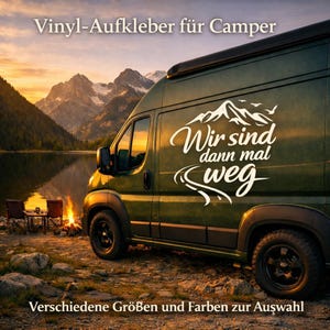 May include: A dark green camper van featuring a white vinyl decal on its side panel. The decal displays a mountain range graphic above the German text 'Wir sind dann mal weg' with a winding road element. The van is parked near a lake at sunset.