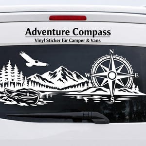 May include: A white vinyl decal applied to the rear window of a white van. The graphic features a mountain range, a forest, a canoe on water, a flying bird, and a compass rose with the letters N, E, S, and W. The text Adventure Compass is above.