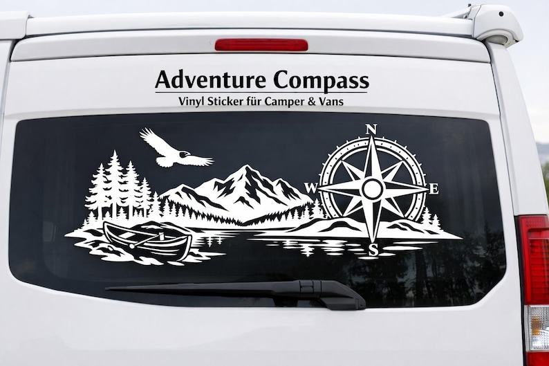 May include: A white vinyl decal applied to the rear window of a white van. The graphic features a mountain range, a forest, a canoe on water, a flying bird, and a compass rose with the letters N, E, S, and W. The text Adventure Compass is above.