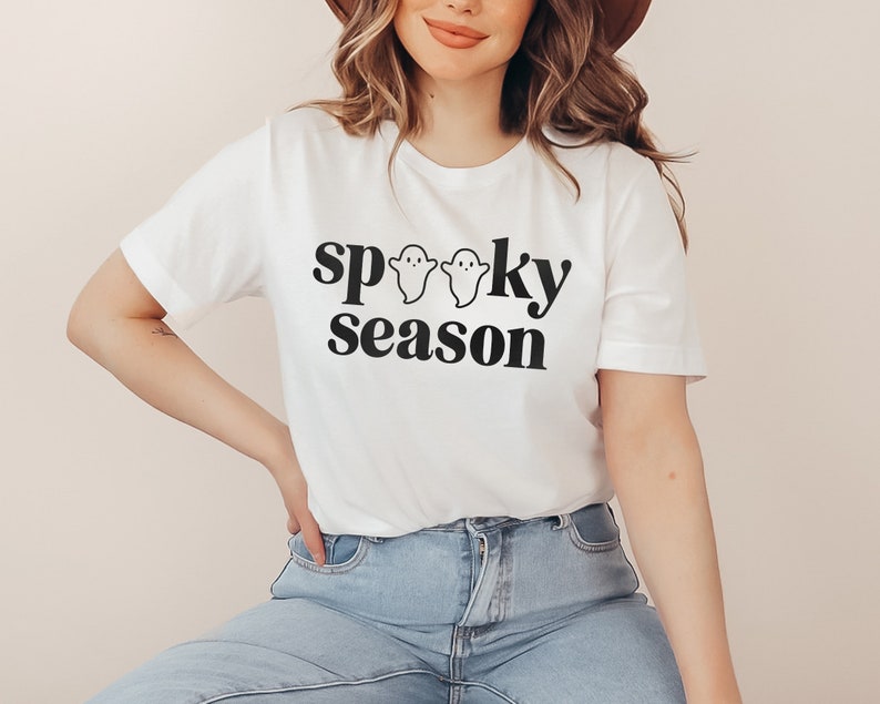 May include: White t-shirt with black text that reads "spooky season" and three small ghost illustrations.