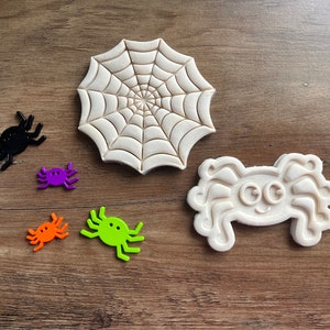 May include: A set of five cookie cutters in the shape of spiders and a spider web. The cutters are made of white plastic and are perfect for making Halloween cookies.