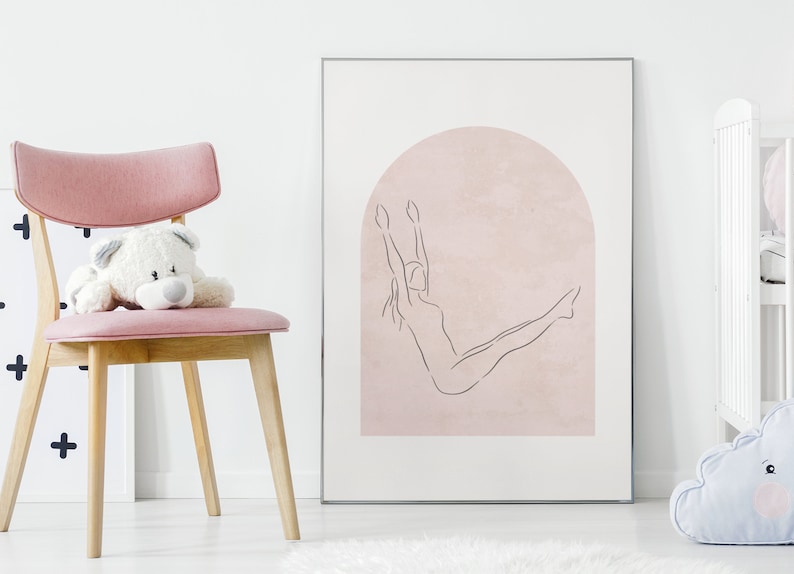 K&ouml;nnte beinhalten: Ein gerahmter Druck eines Strichm&auml;nnchens, das eine Yoga-Pose vor einem rosafarbenen Bogen macht. Der Druck h&auml;ngt an einer wei&szlig;en Wand.