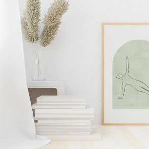 May include: A framed print with a minimalist line drawing of a person doing a side plank exercise. The drawing is on a light green background with a textured arch shape. The frame is light wood.