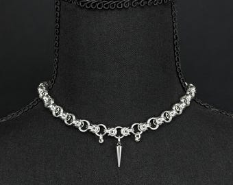 May include: A silver chain necklace with a single pointed spike pendant.