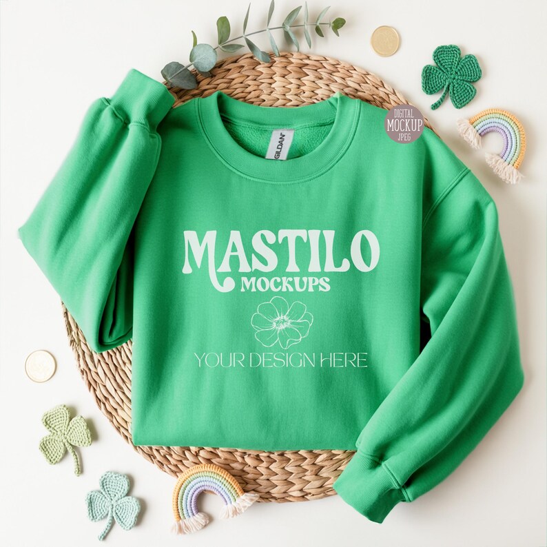 Green Gildan 18000 folded sweatshirt mockup styled with soft shamrock props, perfect for showcasing St. Patrick’s Day or everyday apparel designs in a clean flat-lay layout.