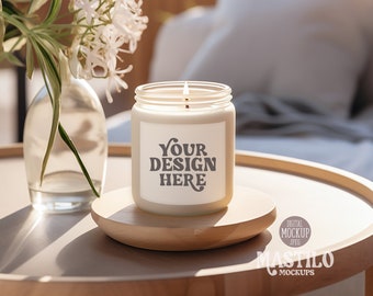 May include: A lit candle in a clear glass jar with a white label that reads "Your Design Here." The candle sits on a small, round wooden stand. A glass vase with white flowers is to the left of the candle.