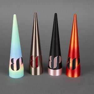 May include: Four cone-shaped objects in a row, each with a different color and design. The colors include a gradient of blue and yellow, bronze, black, and orange. Each cone has a black letter design near the base.