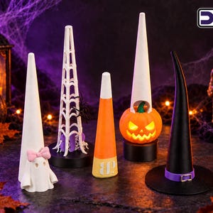 May include: Five cone-shaped ring holders featuring Halloween designs: a white ghost with a pink bow, a white spiderweb structure with a black spider, a candy corn pattern, a glowing orange jack-o'-lantern, and a black witch hat with a purple band.