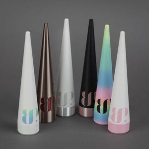 May include: A collection of seven cone-shaped objects in various colors, including white, bronze, black, and a gradient of blue, pink, and yellow. Each object has a logo near the base. The objects have a smooth, matte finish.